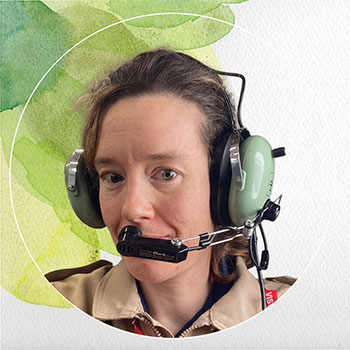 A woman with long hair. She's smiling and wearing heavy duty headset.